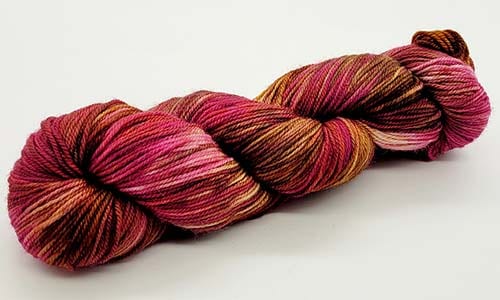 A skein of variegated yarn featuring shades of pink, red, and brown. The yarn, perfect for all Nerds with Needles, is twisted into a neat bundle and set against a plain white background.
