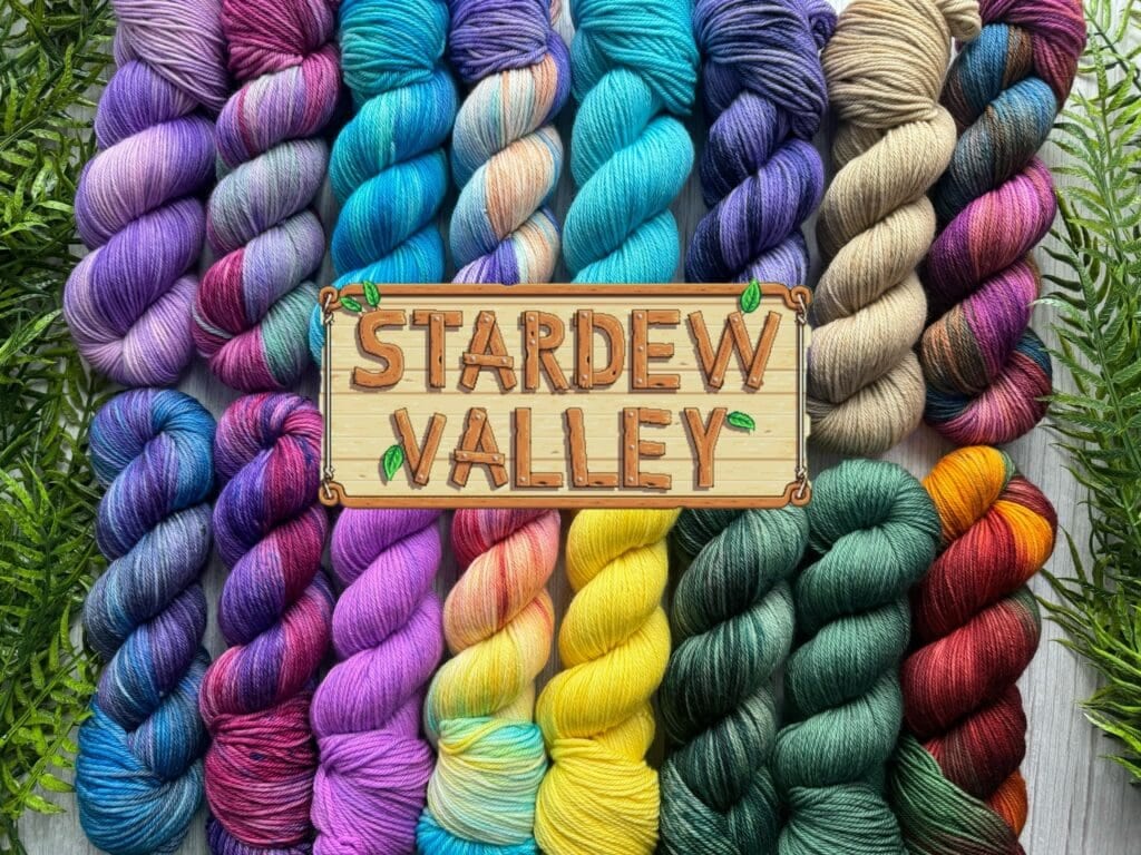A collection of colorful yarn skeins and knits arranged around a wooden sign reading 